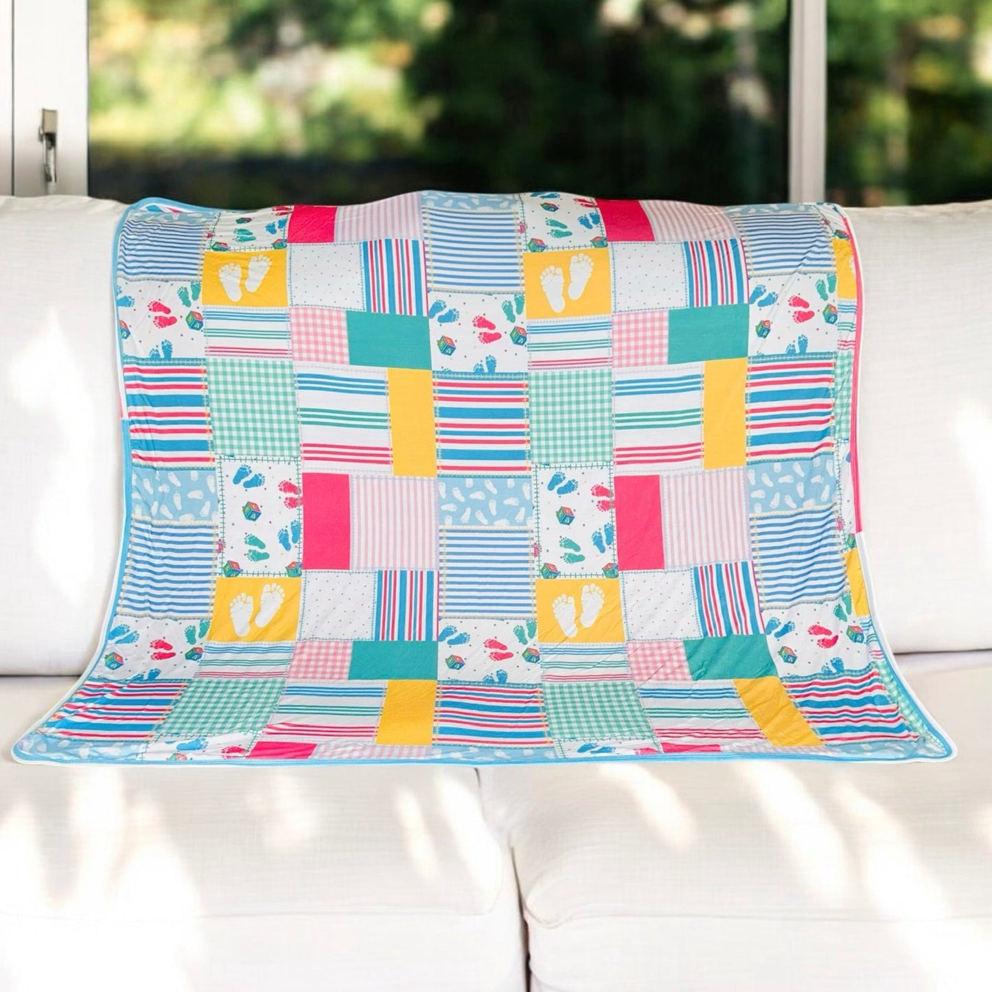 Colorful patchwork Newborn Memories Bamboo Blanket with baby footprints and stripes, made of soft, stretchy bamboo viscose blend.