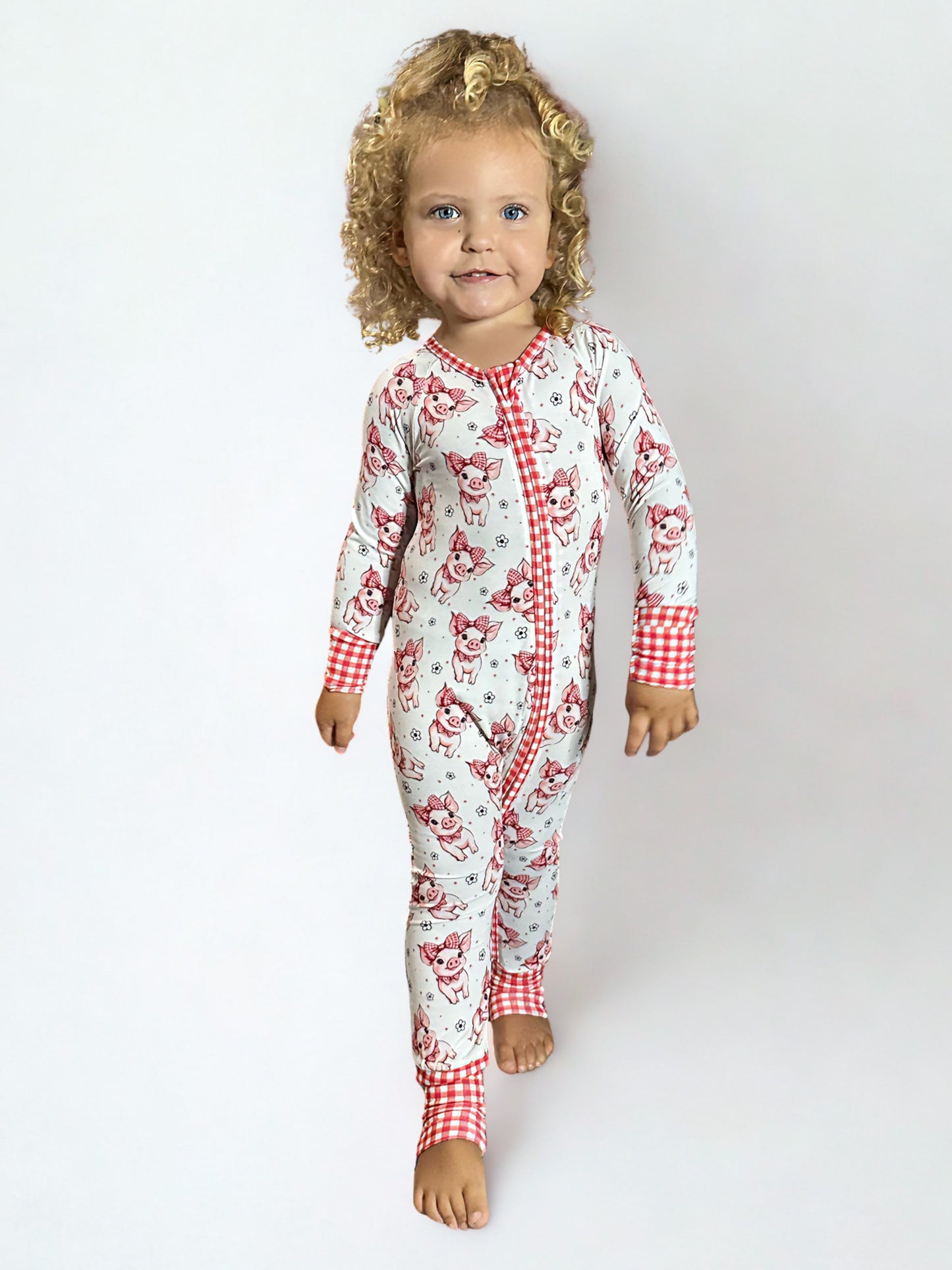 Child wearing a red and white patterned bamboo onesie on a plain background