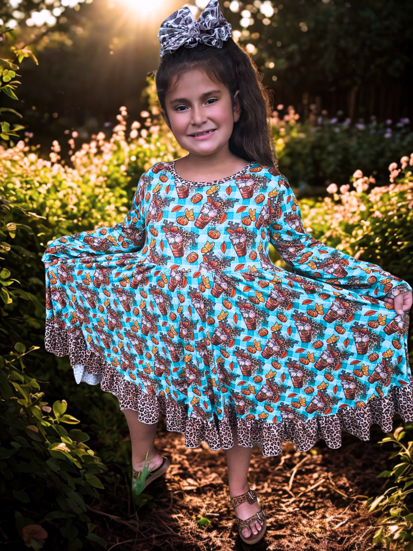 Young girl in a patterned dress standing outdoors with flowers and trees in the background