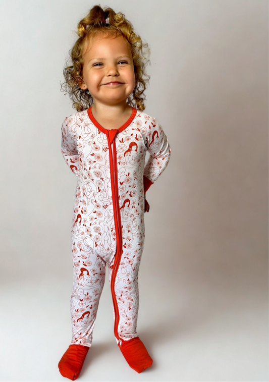 Beautiful Bond Bamboo Romper on smiling child, featuring red accents and playful pattern.