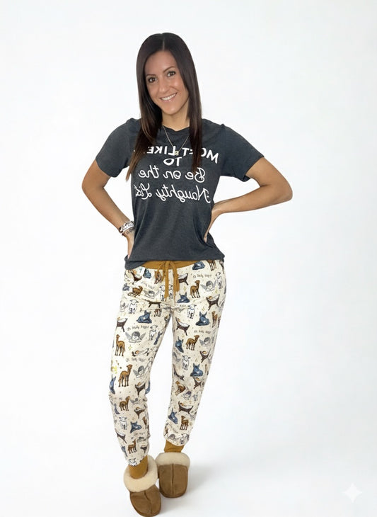 Woman wearing a dark gray t-shirt with text and patterned pants on a white background