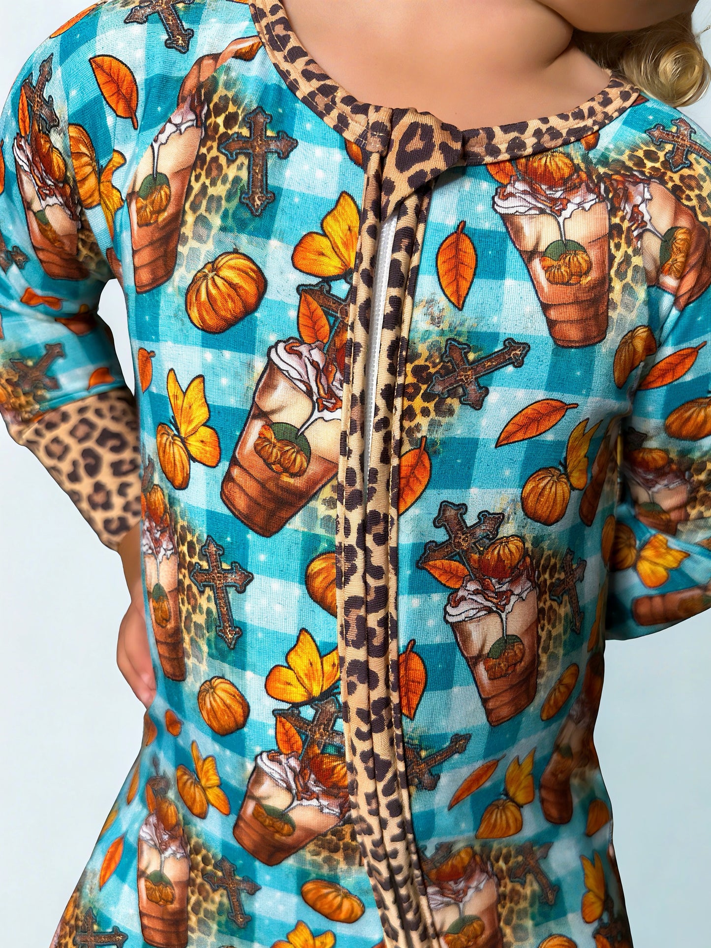 Close-up of a colorful outfit with autumn-themed patterns on a blue background. A child wearing a fall bamboo romper.