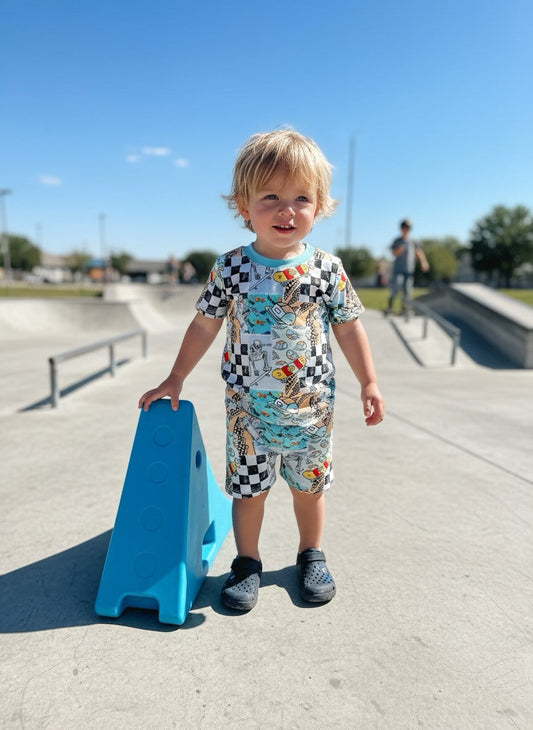 Toddler wearing Skater Boy Bamboo two piece short sleeve and short set with colorful skate design at skate park
