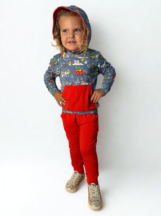 Child wearing a patterned long-sleeve shirt and red pants on a white background