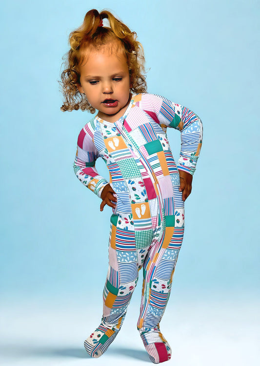 Toddler wearing colorful Newborn Memories Bamboo Romper with double-sided zipper against blue background