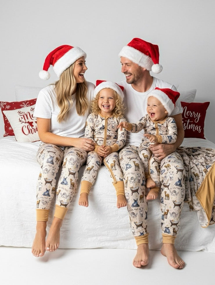 Family of four wearing matching Christmas pajamas and hats on a bed.