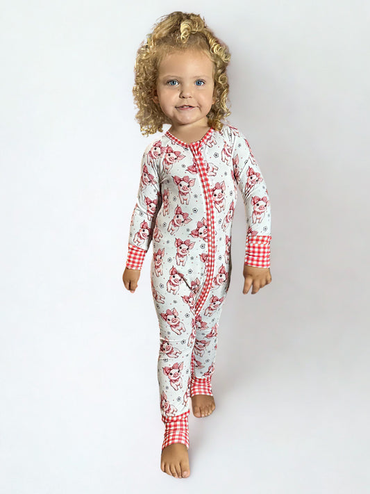 Child wearing a red and white patterned bamboo onesie on a plain background