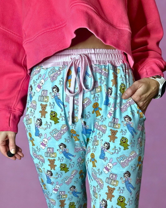 Person wearing pink sweatshirt and colorful pajama pants with cartoon characters on a purple background