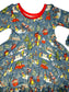 Children's dress with winter scene print featuring snowmen, cars, and trees on a blue background.