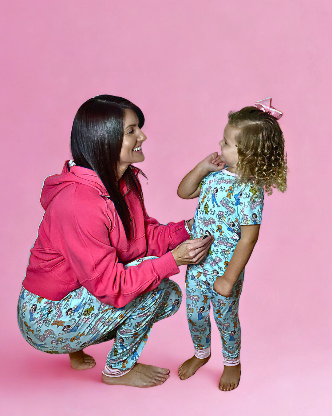 Woman and child wearing matching pajamas against a pink background