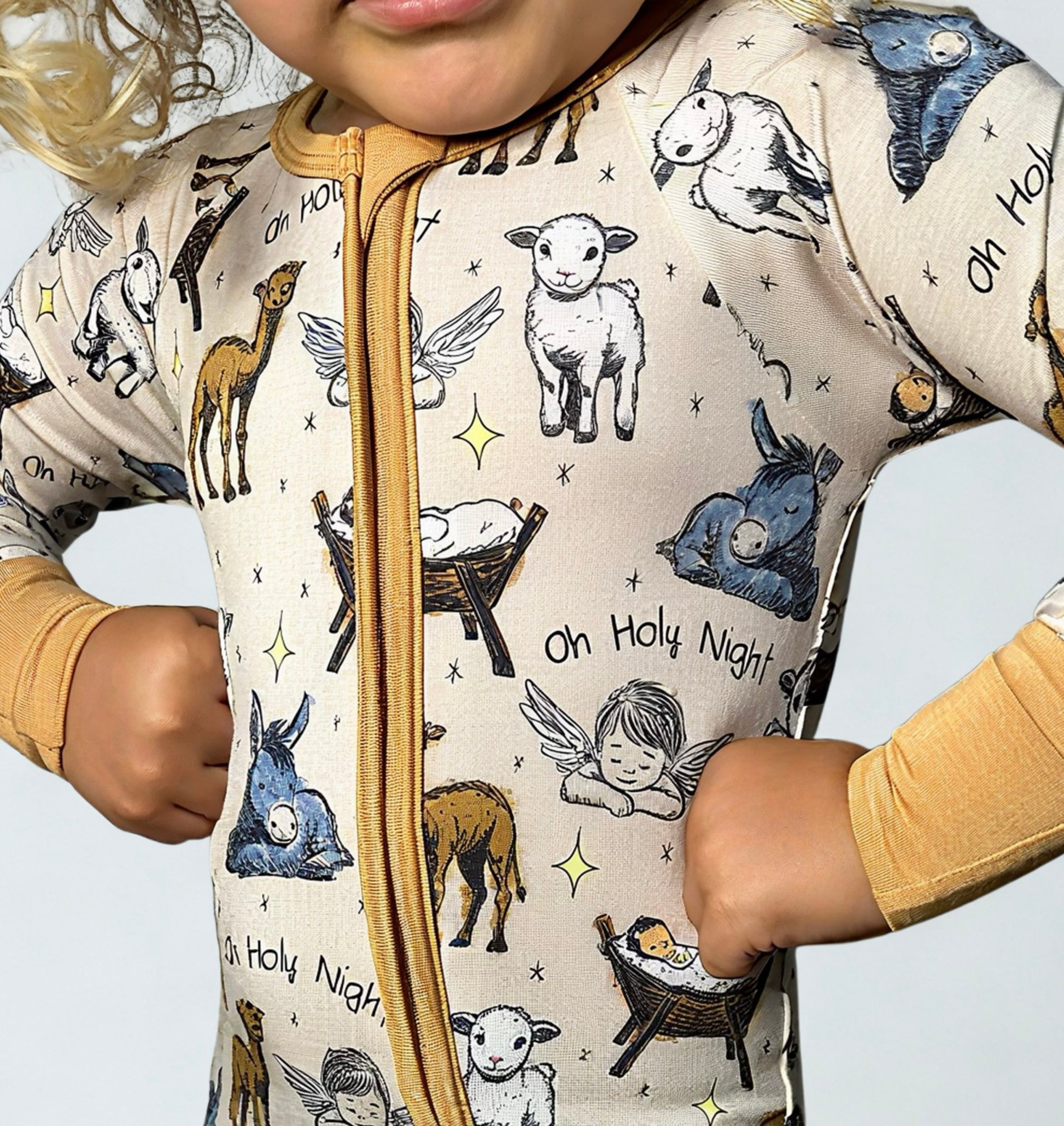 Child wearing a onesie with Christmas-themed animal illustrations on a light background