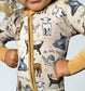 Child wearing a onesie with Christmas-themed animal illustrations on a light background