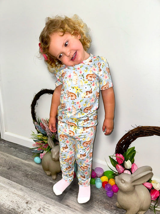Toddler wearing Bunny Blooms Two Piece Set with floral design, surrounded by spring decor.