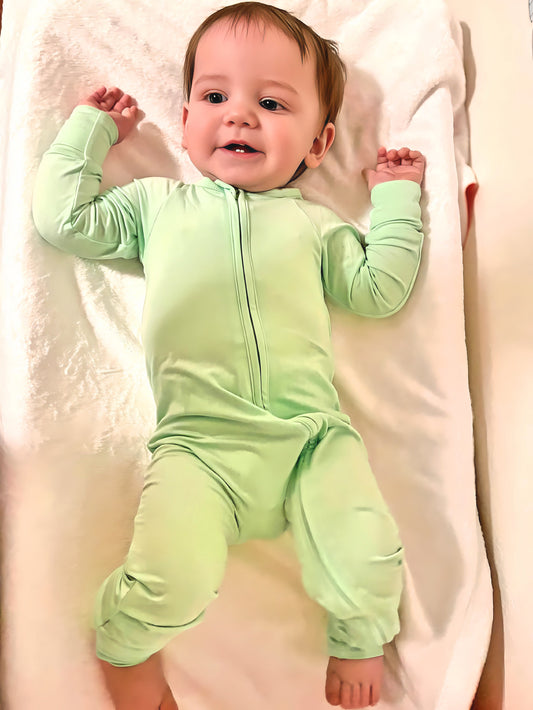 Mint green solid bamboo romper with double-sided zipper on a baby lying down.