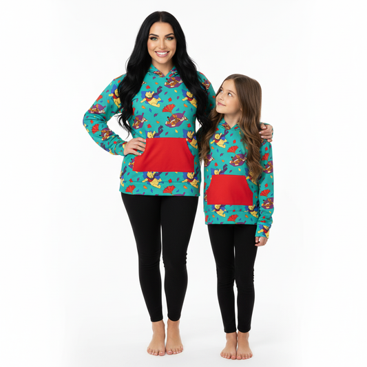 Woman and child wearing matching teal pajama sets with red pockets on a white background