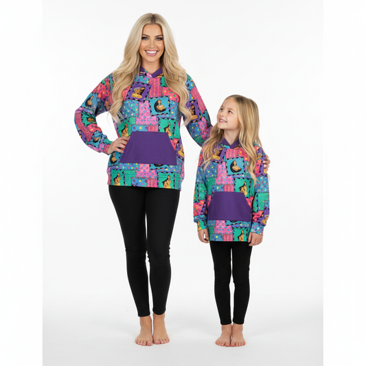 Two people wearing colorful patterned pullovers and black leggings on a white background